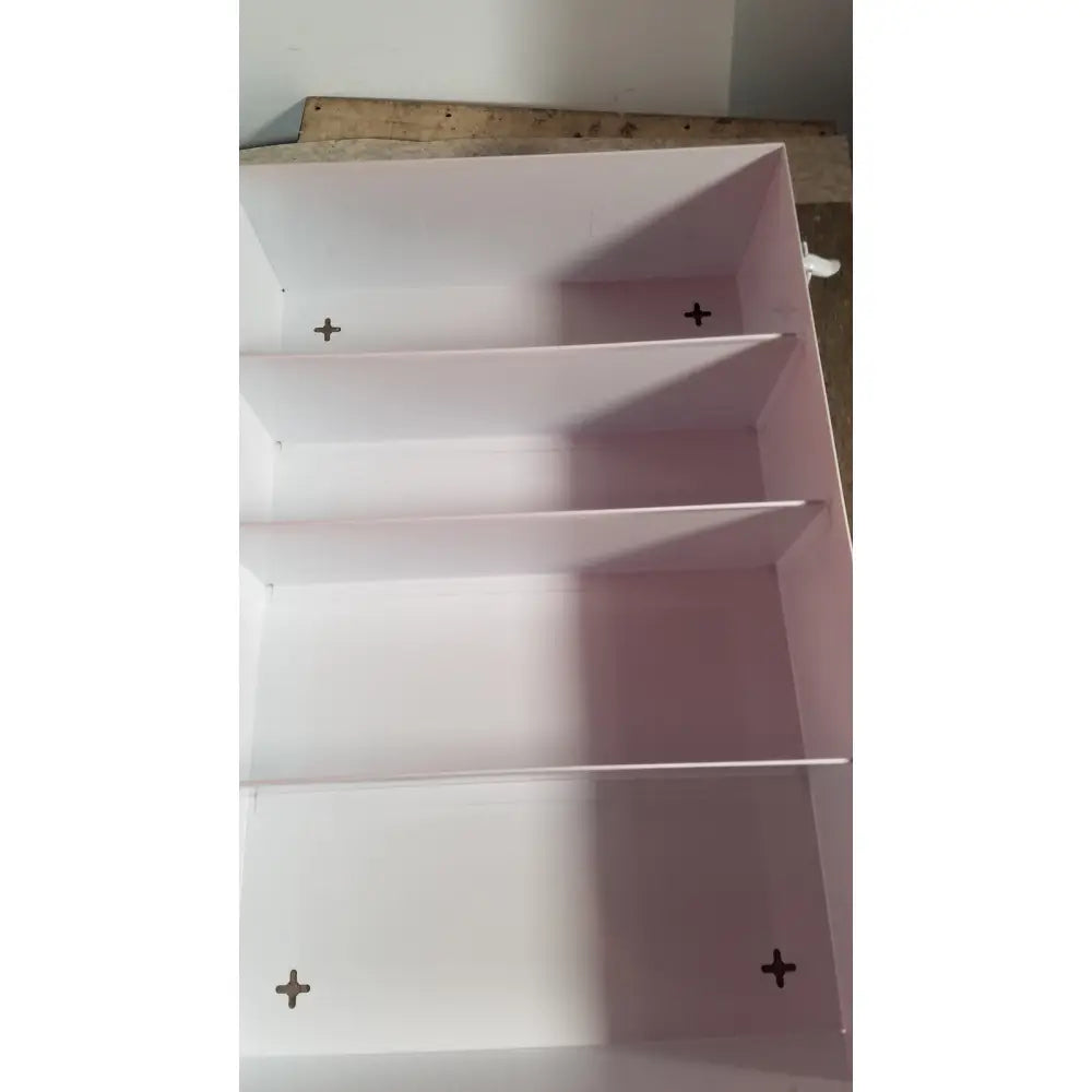 Pink empty uline h-5951 3-shelf aid cabinet with four compartments and black cross-shaped mounting marks on each shelf