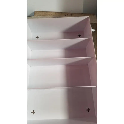 Pink empty uline h-5951 3-shelf aid cabinet with four compartments and black cross-shaped mounting marks on each shelf