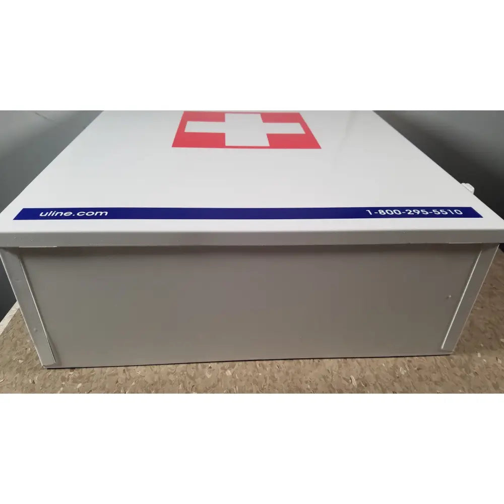 White metal aid cabinet uline h-5951 3-shelf with red cross emblem and blue uline.com label and phone number