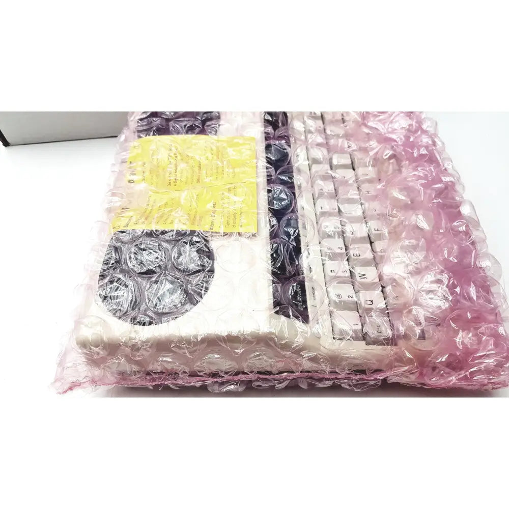 A white ultratec superprint 4425 e-turbo telephone printer tty keyboard wrapped in pink bubble wrap with a yellow label