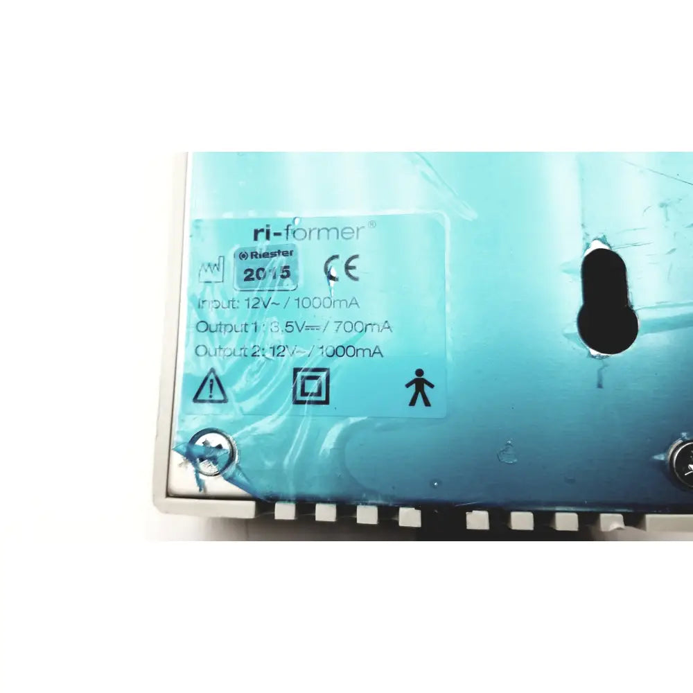 Blue plastic power adapter labeled ri-former by riester on the back side of an ulvac air compressor unit model