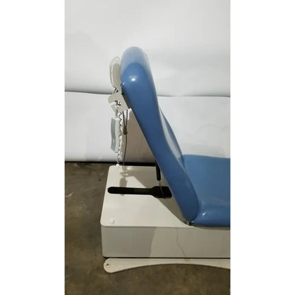 Blue padded UMF 4070 power table with white base adjustable headrest and hand control for reuse medical settings