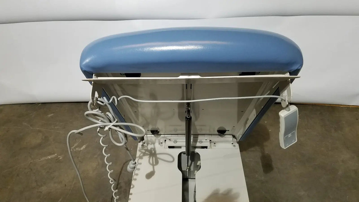 Blue upholstered headrest on white industrial ironing station of umf 4070 power table with hand control medical equipment