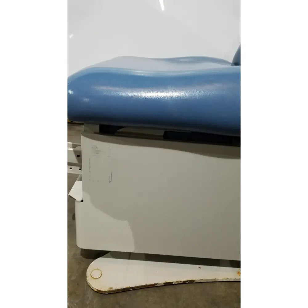 Blue padded reuse medical power table with white metal frame and hand control for adjustable examination use