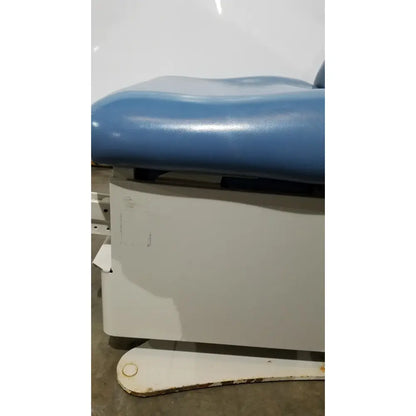 Blue padded reuse medical power table with white metal frame and hand control for adjustable examination use