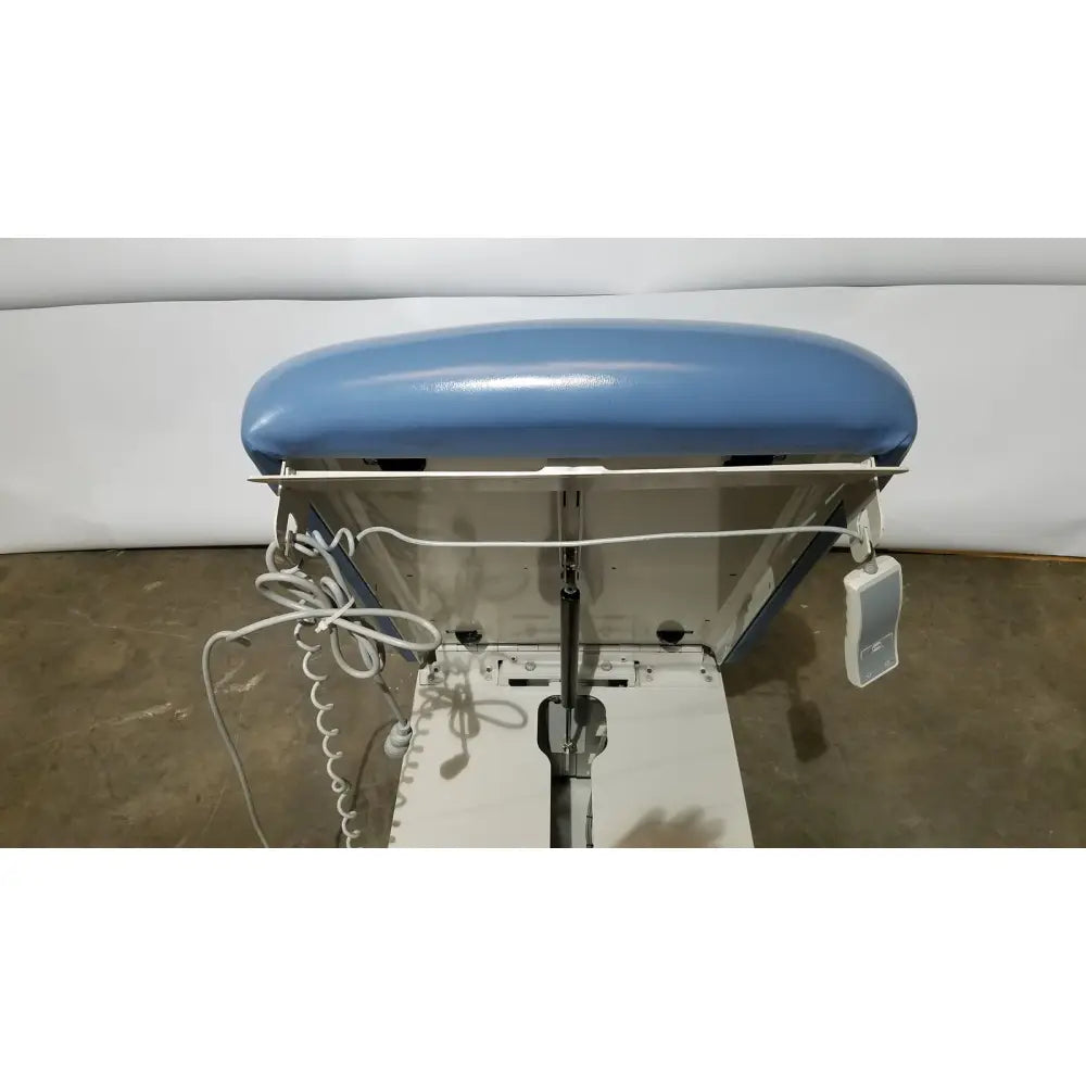 Blue upholstered headrest on white industrial ironing station of umf 4070 power table with hand control medical equipment
