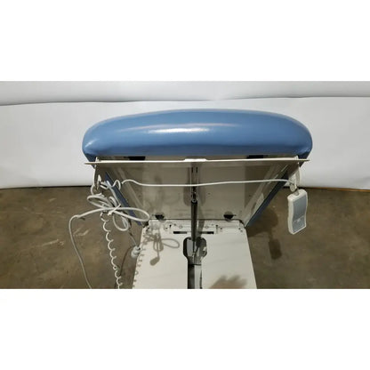 Blue upholstered headrest on white industrial ironing station of umf 4070 power table with hand control medical equipment