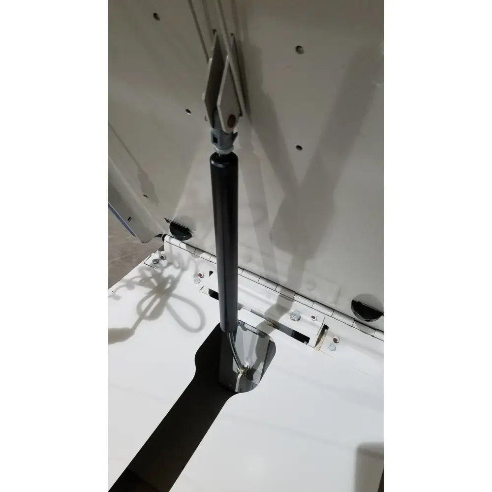 Black gas spring with metallic end caps attached to white cabinet on umf 4070 power table with hand control for reuse medical