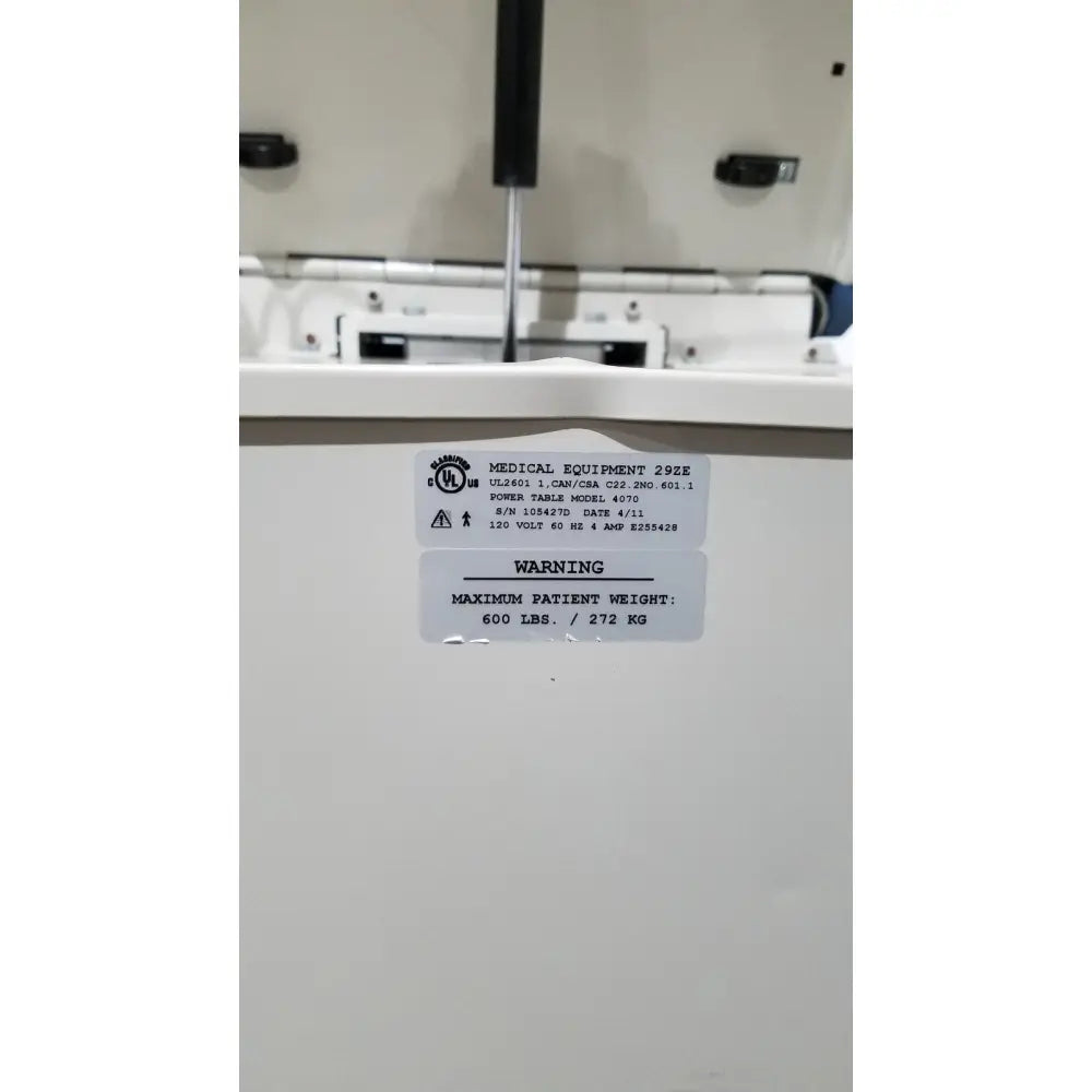 White umf 4070 power table with hand control showing medical equipment specifications and patient weight warning label