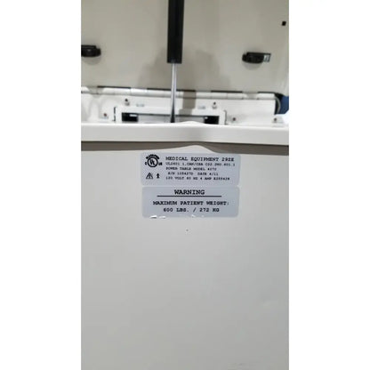 White umf 4070 power table with hand control showing medical equipment specifications and patient weight warning label