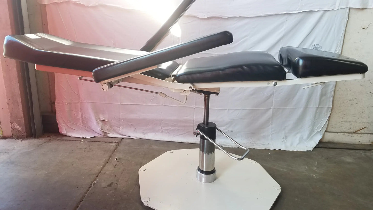 Black padded umf medical 8675 adjustable phlebotomy chair with adjustable sections and white octagonal base
