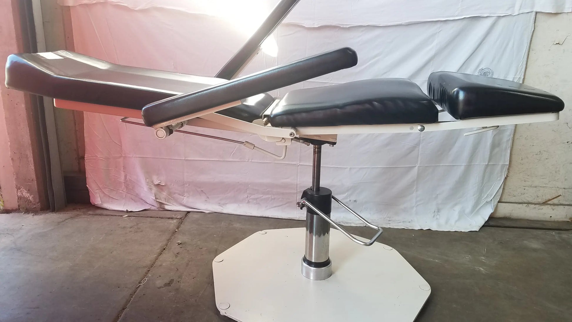 Black padded umf medical 8675 adjustable phlebotomy chair with adjustable sections and white octagonal base