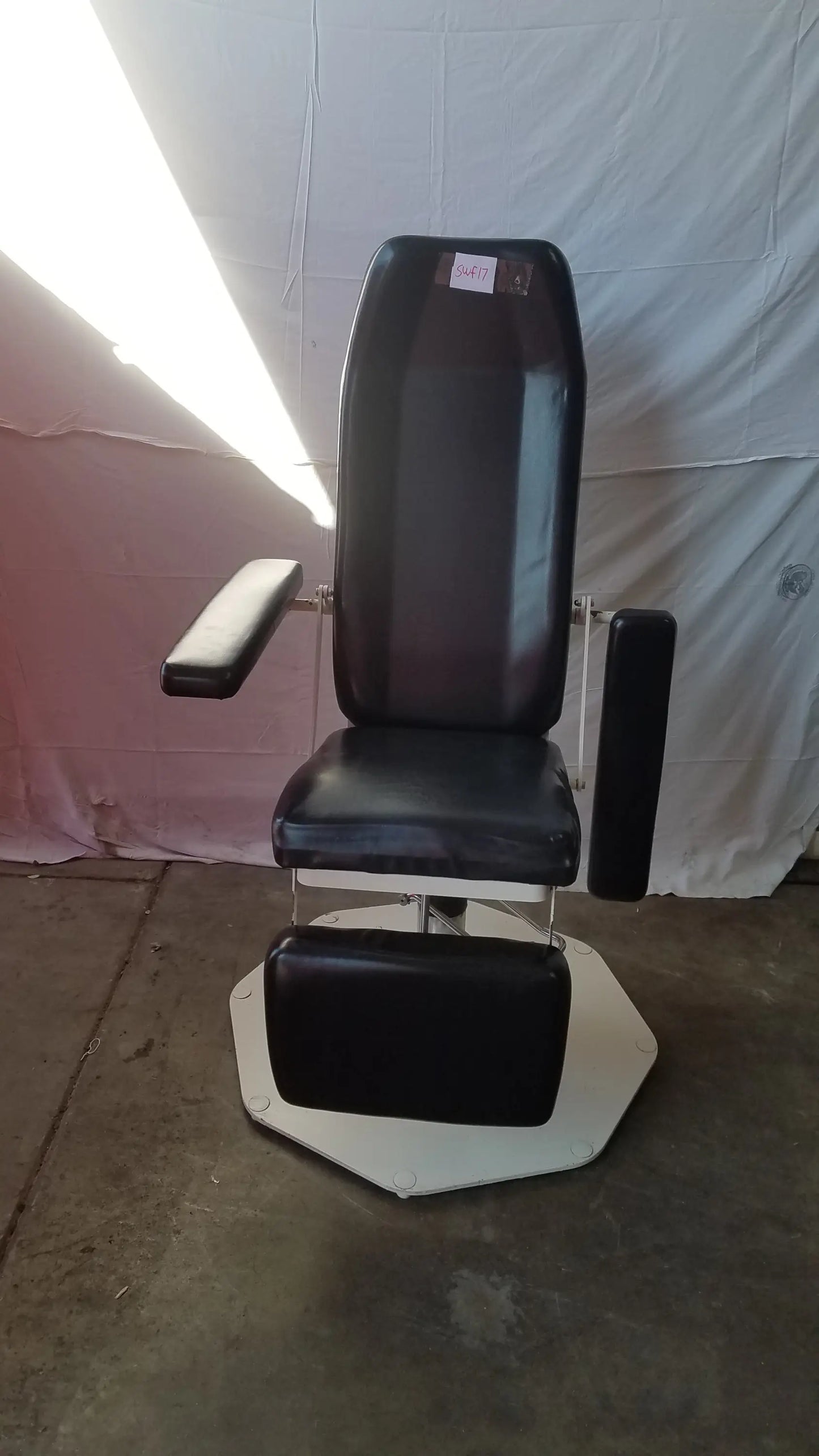 Black leather adjustable phlebotomy chair with chrome frame and white octagonal base for medical use