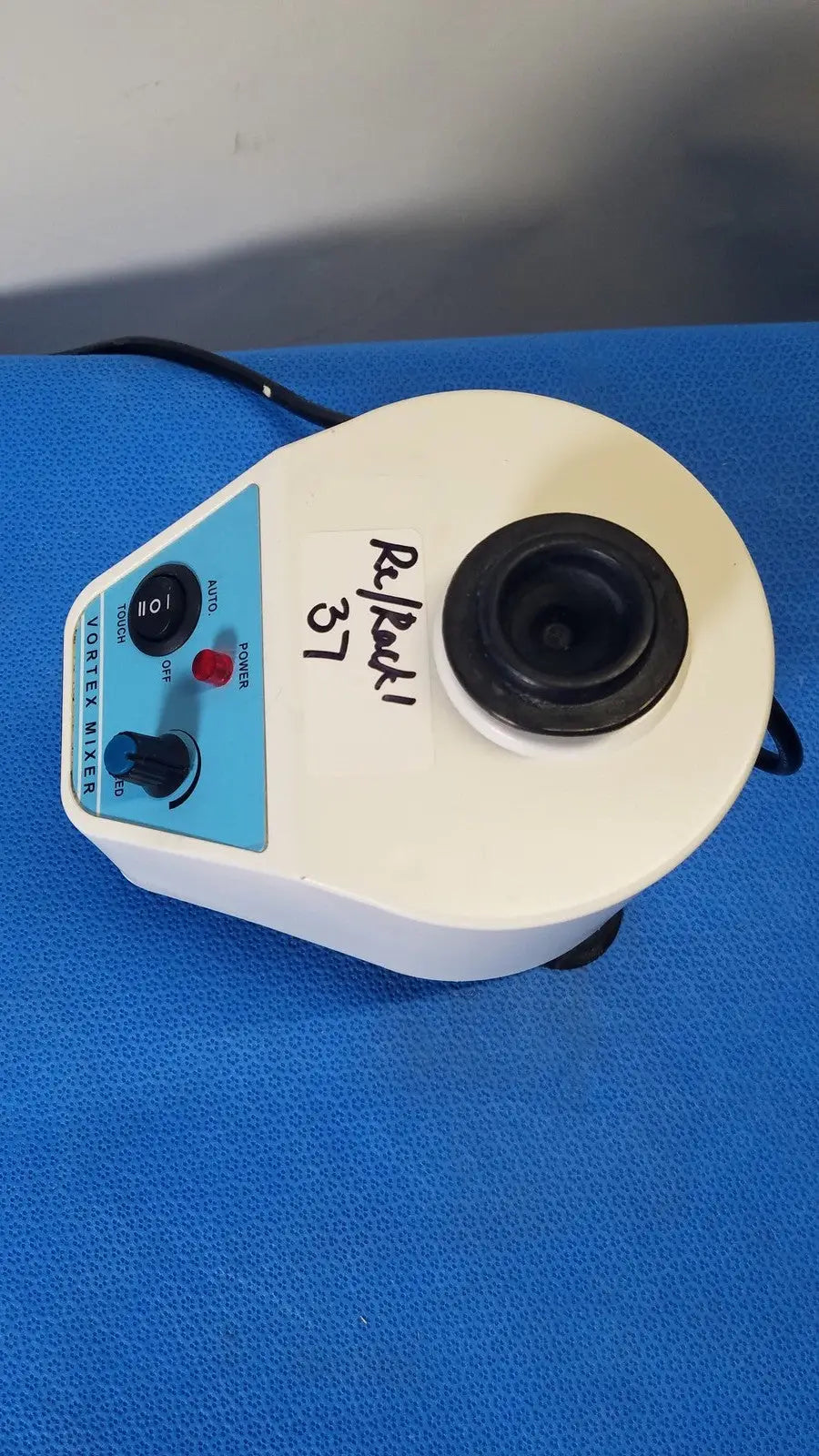 White plastic unico vortex mixer l-vm 100 with blue control panel and black rotor chamber showing back side label