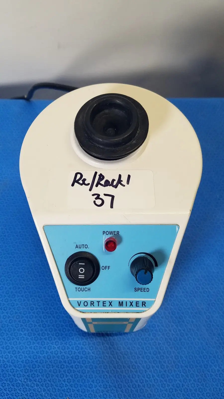 Unico vortex mixer L-VM 100 with white and light blue body and black rubberized top labeled re/rock 37