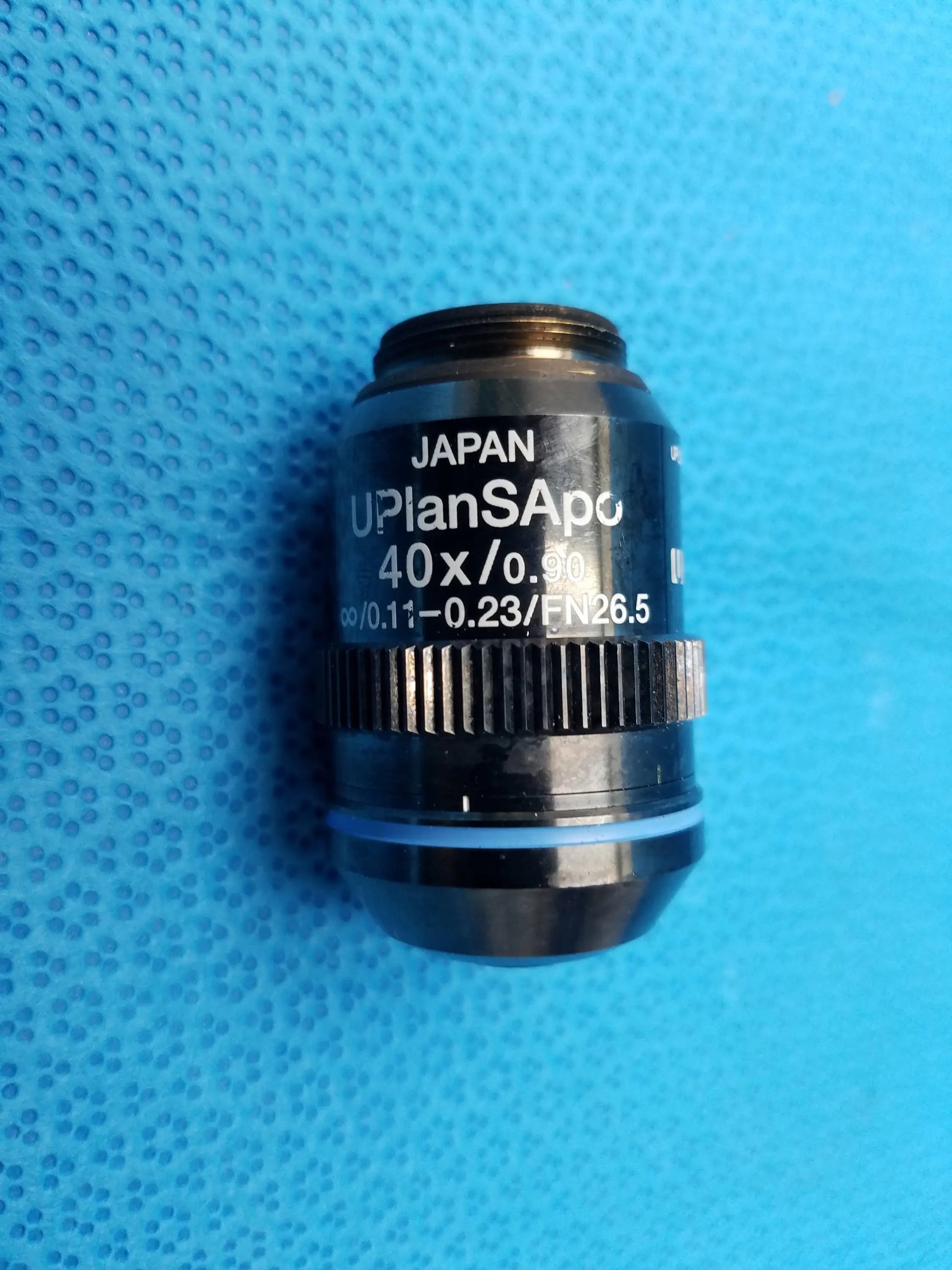 Black uplanapo 40x/0.90 microscope objective lens with textured focusing ring and blue accent band featuring numerical aperture and field number