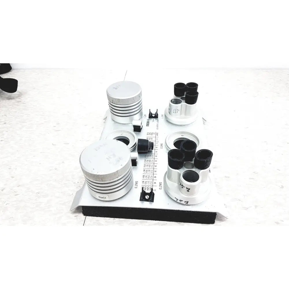 White laboratory-grade salt solution holder with black caps and silver rings in vaisala hmk15 humidity calibrator