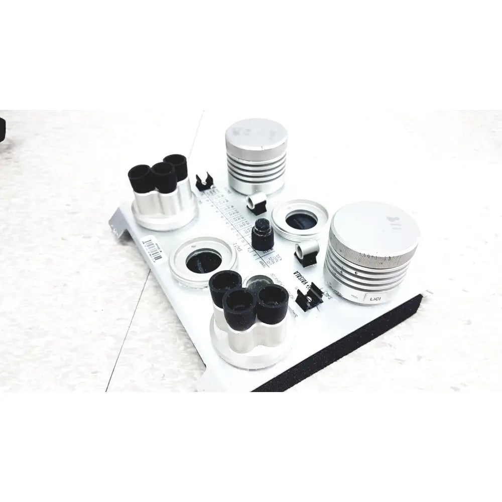 Silver cylindrical lens components with black caps and threaded rings on white plate in vaisala hmk15 humidity calibrator