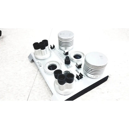 Silver cylindrical lens components with black caps and threaded rings on white plate in vaisala hmk15 humidity calibrator