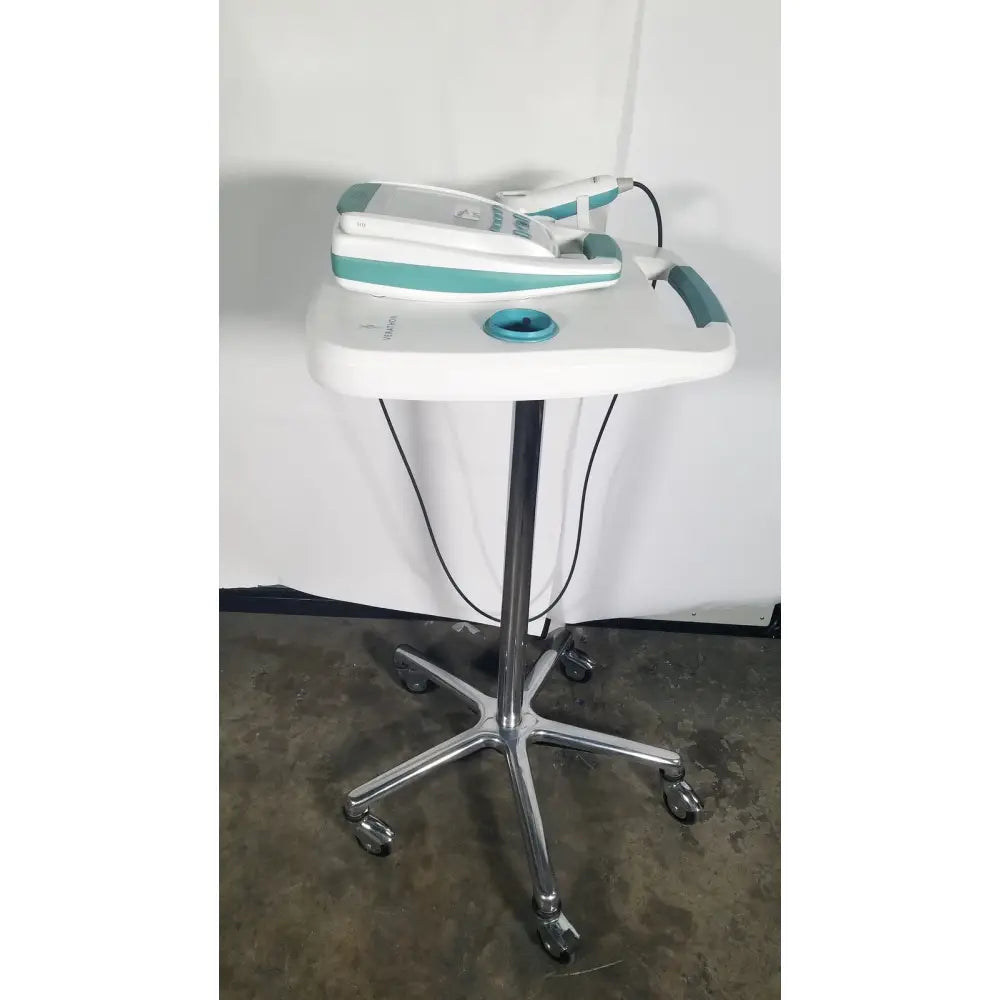 White and teal medical-grade dental handpiece resting on chrome-legged cart with verathon bladderscan stand reuse medical use