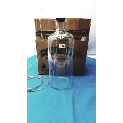 Vintage 9 inch clear glass bottle with black cork stopper and embossed coming lettering, timeless decorative piece
