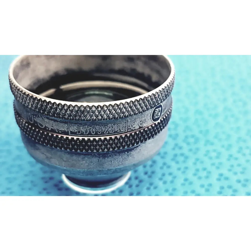 Silver-toned textured camera lens mount with engraved markings on the back of the volk super quad ophthalmic laser lens