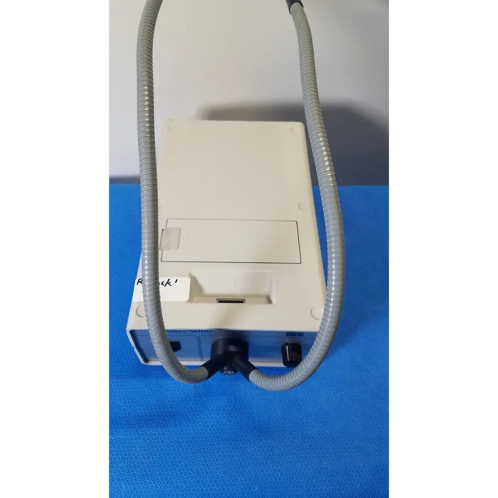 White and blue Volpi Intralux 5000 fiber optic illuminator with two gray corrugated hoses showing illuminator dual gooseneck