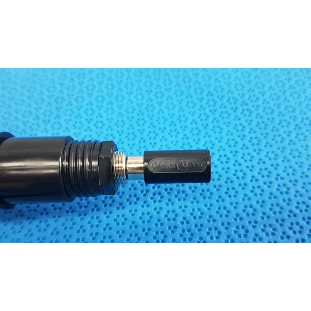 Black Welch Allyn fuel injector nozzle with metallic threaded connection and engraved branding for illuminator bulb cable use