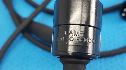 Black metal lamp socket with engraved text and rubberized grip on the back side of welch allyn power adapter plug