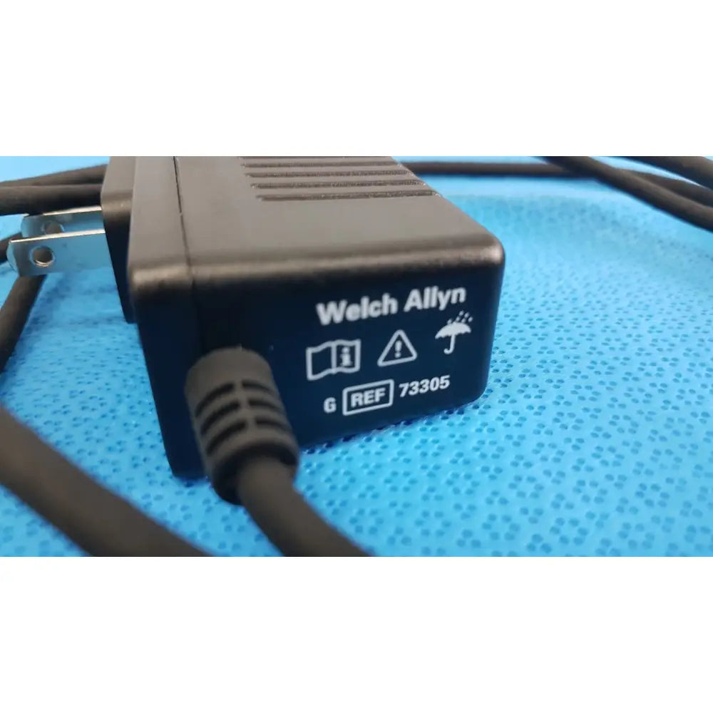 Welch allyn 73305 6v power adapter plug with textured plastic casing and coiled black cord for medical devices