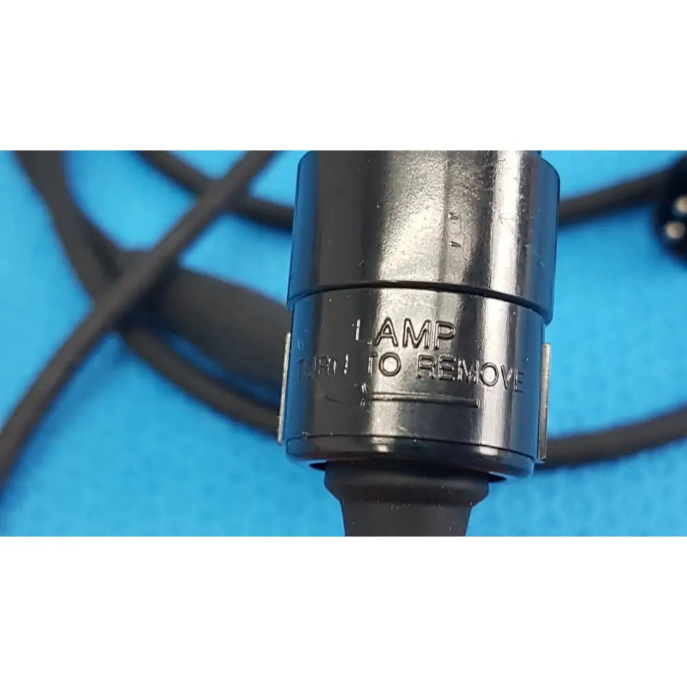 Black metal lamp socket with engraved text and rubberized grip on the back side of welch allyn power adapter plug