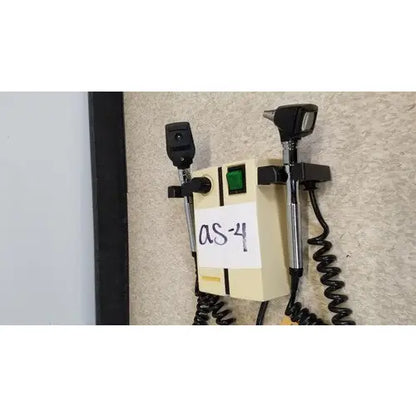 Beige wall-mounted welch allyn transformer otoscope ophthalmoscope with black handles and coiled cords for medical use