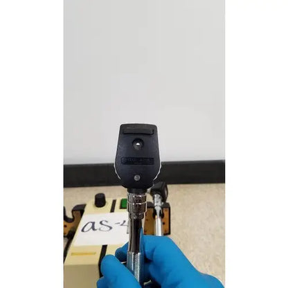 Welch Allyn black and silver transformer otoscope ophthalmoscope held in gloved hand for medical examination