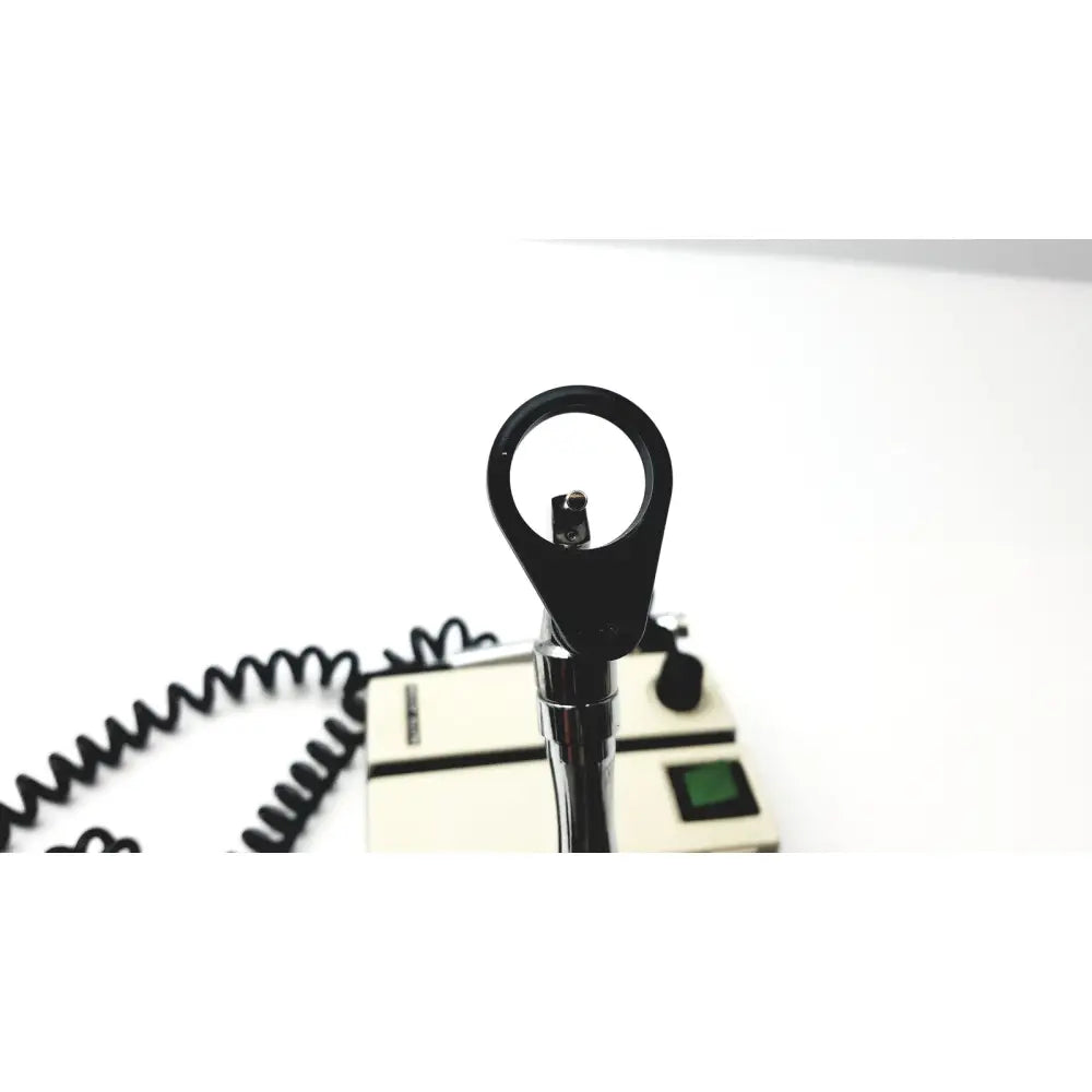 Black handheld welch allyn transformer ophthalmoscope otoscope with chrome handle and coiled cable beside beige base unit