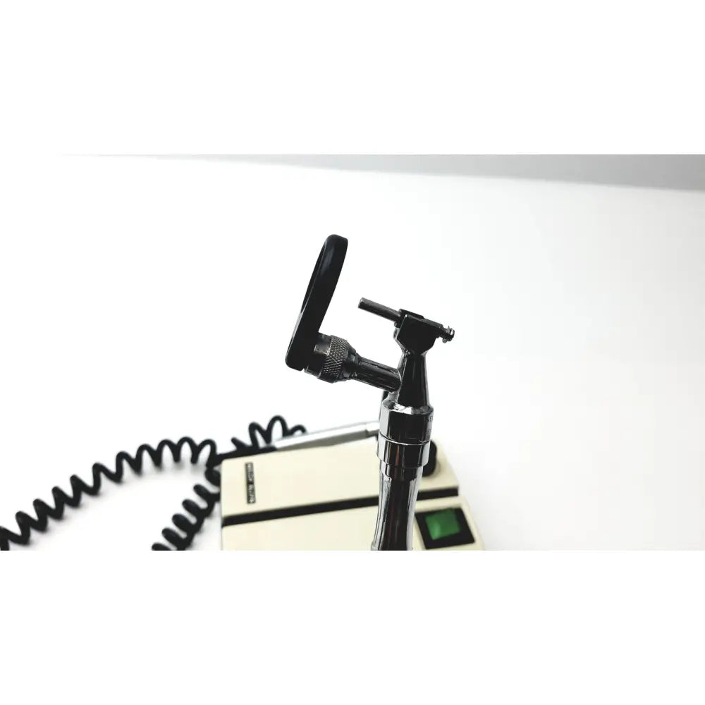 Black metal welch allyn transformer ophthalmoscope otoscope with curved handle and adjustable head on beige wall transformer base