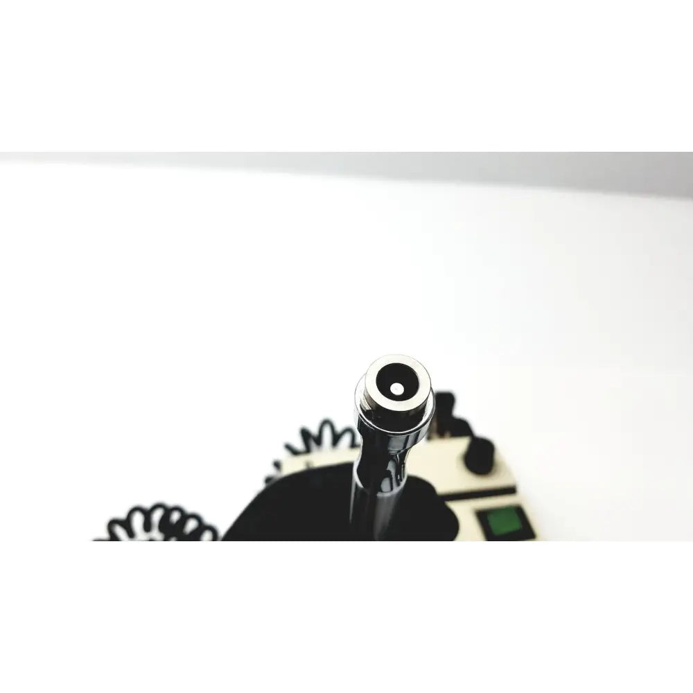 Shiny chrome vape pen with sleek cylindrical design and black mouthpiece next to welch allyn 74710 wall transformer ophthalmoscope otoscope