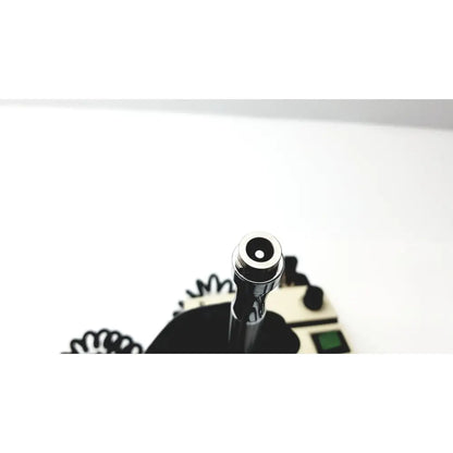 Shiny chrome vape pen with sleek cylindrical design and black mouthpiece next to welch allyn 74710 wall transformer ophthalmoscope otoscope