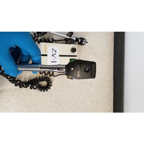 Black handheld Welch Allyn ophthalmoscope with silver metallic handle and coiled cable for wall transformer reuse medical use