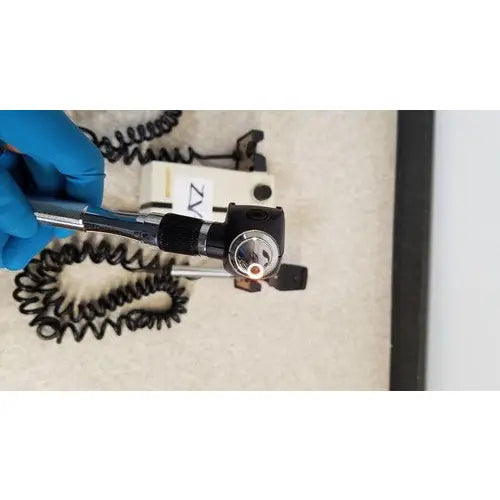 Black Welch Allyn otoscope with circular lens housing and coiled metal cable for wall transformer reuse medical use