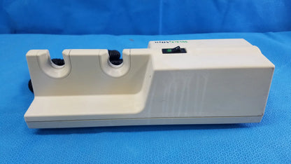 White plastic electric knife sharpener with two slots and black power switch compatible with welch allyn wall-mounted diagnostic power units without instrument heads