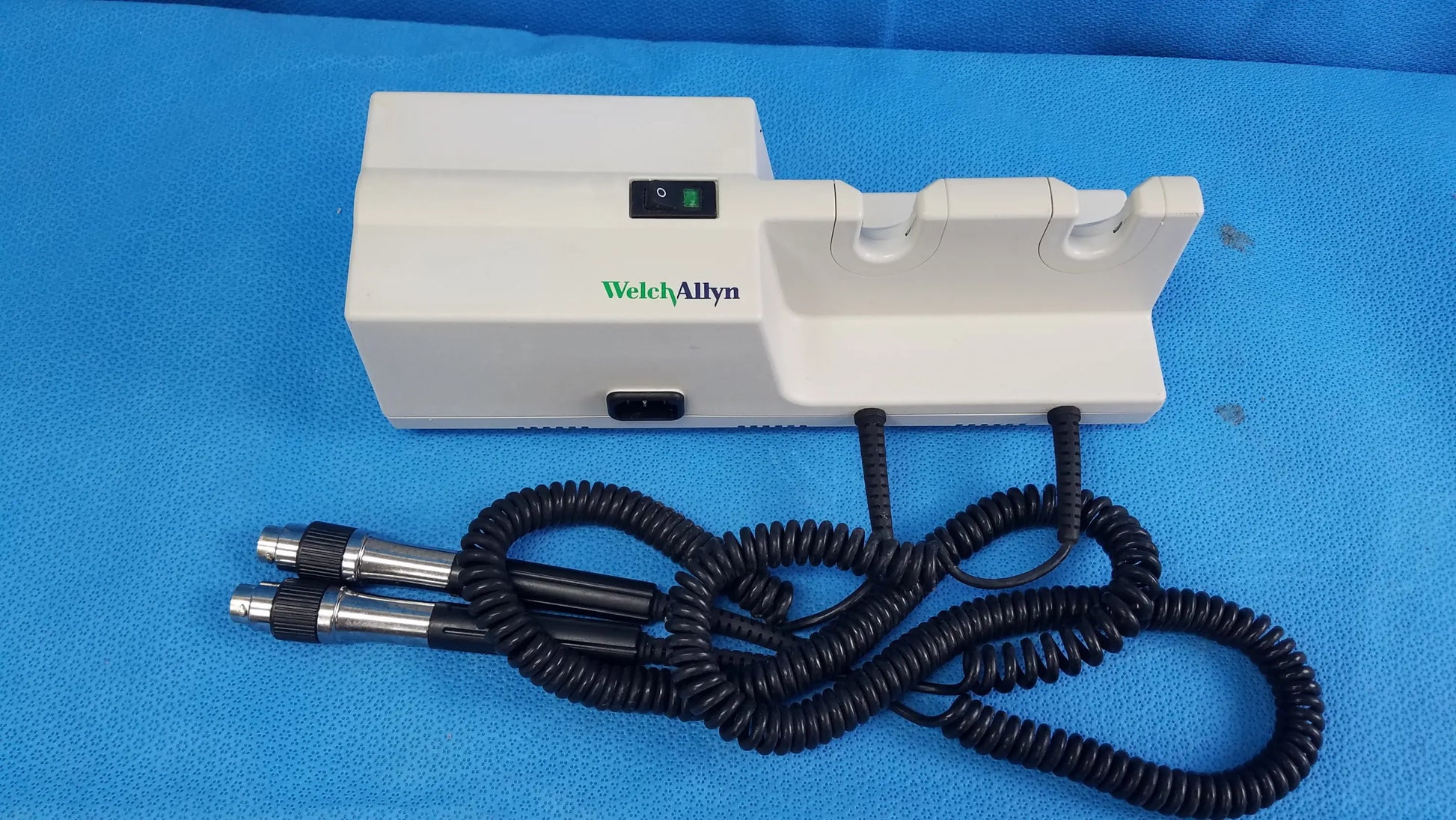 White Welch Allyn 767 series transformer with two black coiled cords and metallic probes for wall-mounted diagnostic power without instrument heads