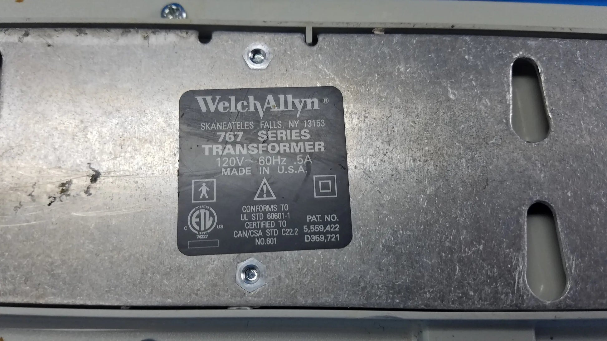 Black rectangular label on metallic surface showing welch allyn 767 series transformer for wall-mounted diagnostic power without instrument heads