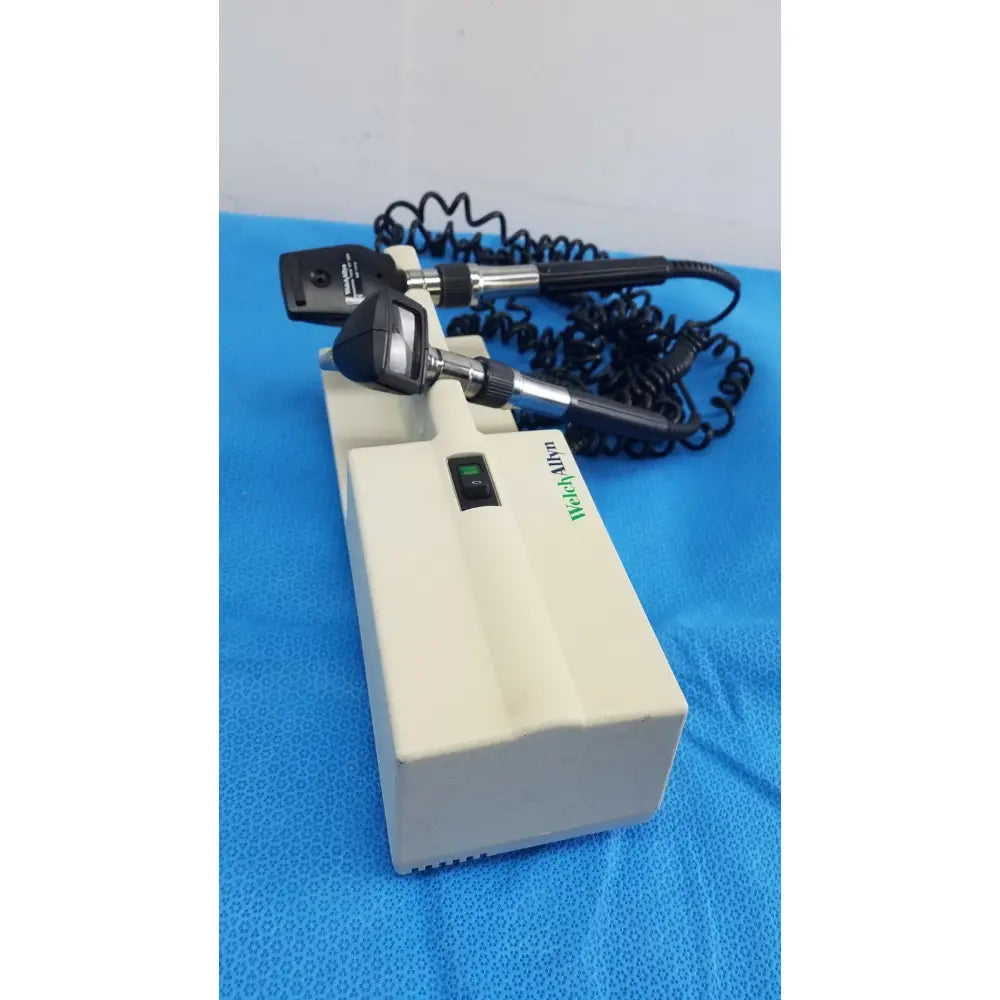 Medical-grade black and silver ophthalmoscope mounted on beige base unit with welch allyn 767 series wall transformer