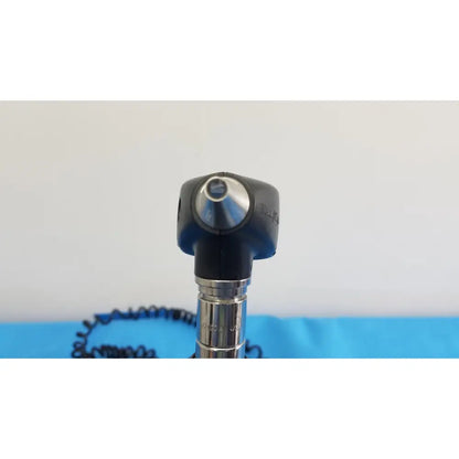Black and silver otoscope with rounded head metallic shaft and coiled cable from welch allyn 767 series wall transformer