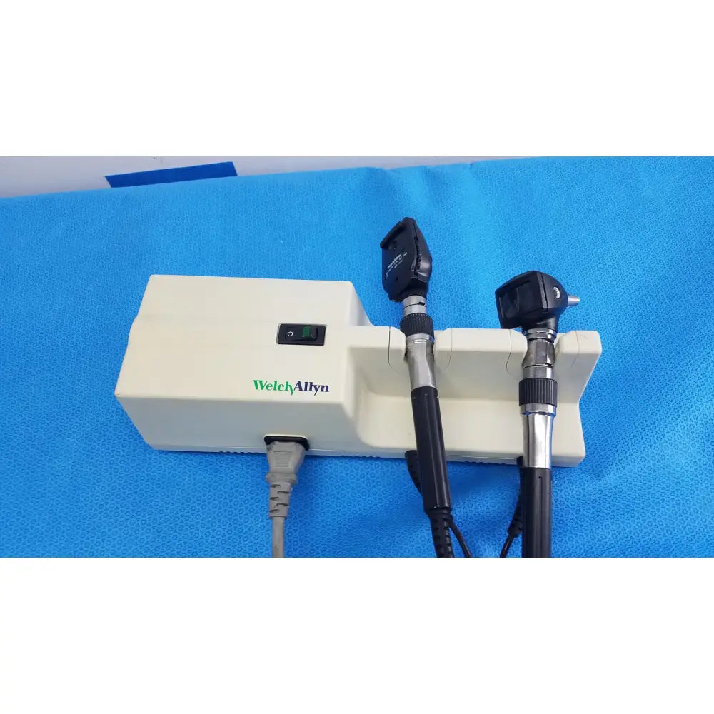 Welch Allyn 767 series wall transformer with black and silver otoscope handles mounted on white base unit