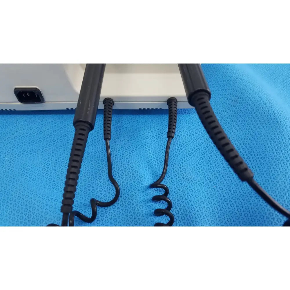 Black coiled cables with textured ribbed connectors at the back of welch alleyn 767 series wall transformer device