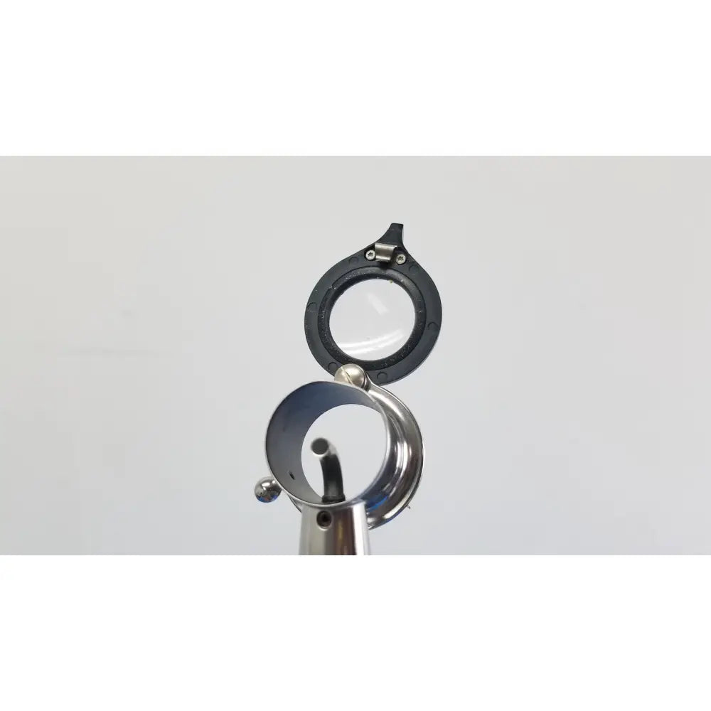 Black-rimmed magnifying glass with metallic reflective base and hinge in welch allyn wall transformer with coaxial ophthalmoscope