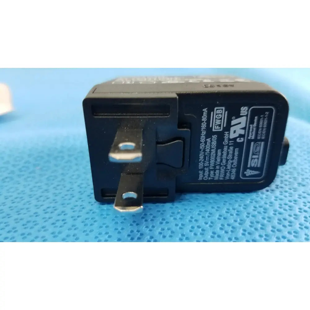 Black plastic travel adapter with silver prongs and regulatory markings for welch allyn kleenspec cordless led system charging station