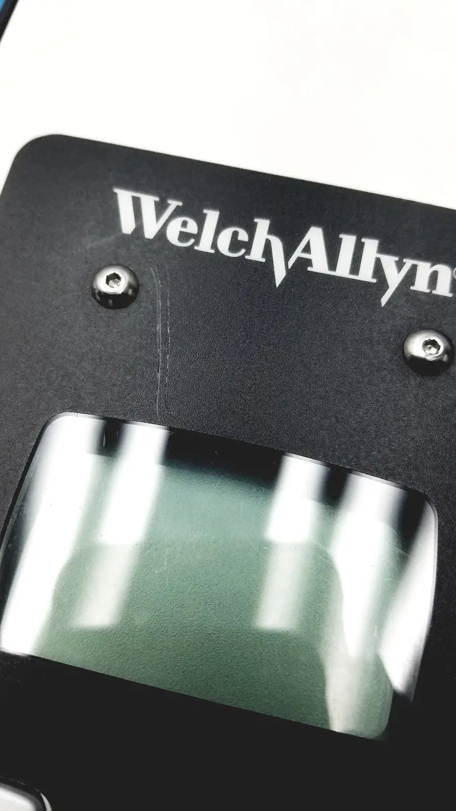 Black welch allyn plus calibration tester with rectangular transparent window and silver screws on medical device