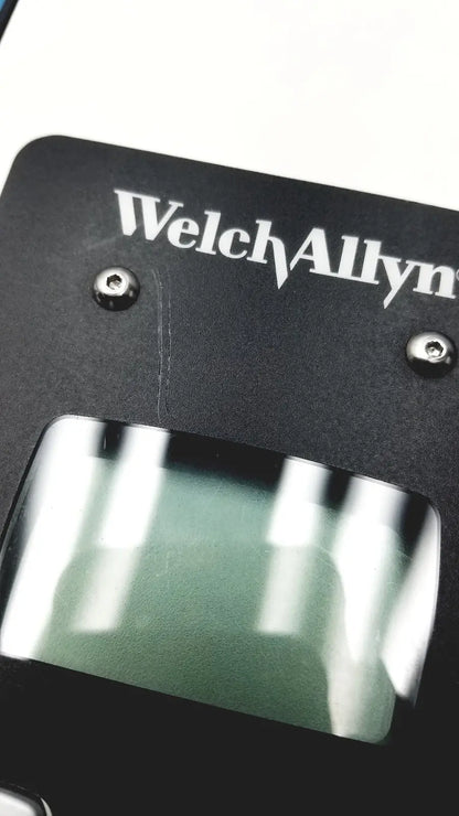 Black welch allyn plus calibration tester with rectangular transparent window and silver screws on medical device